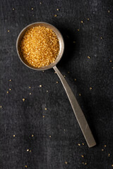 Big old spoon with brown sugar on black background