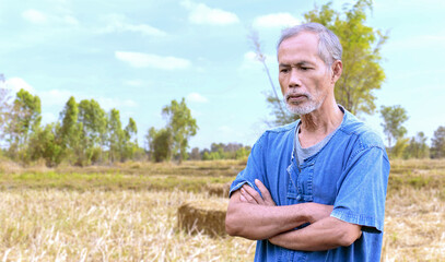 Naklejka na ściany i meble Portrait of an elderly Asian farmer worried about the weather for farming.
