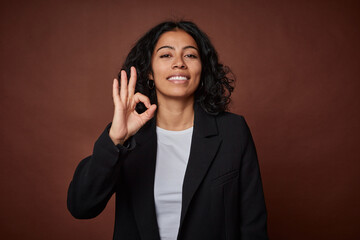 A young business colombian woman cheerful and confident showing ok gesture.