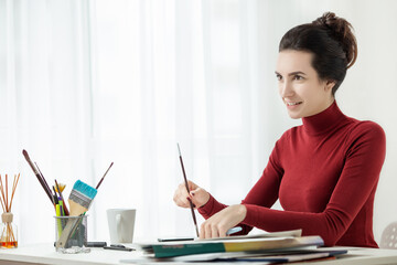 girl in red clothes is sitting in the office. One young woman only. artist's workplace