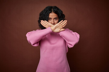 Young colombian curly hair woman isolated on brown background doing a denial gesture