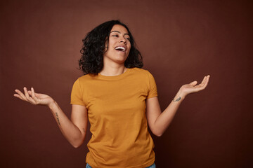 Young colombian curly hair woman isolated on brown background joyful laughing a lot. Happiness...