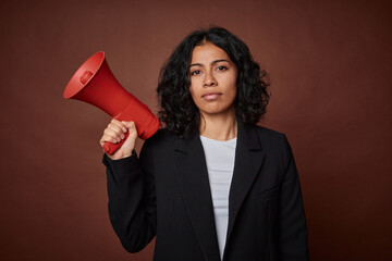 A young business woman passionately advocates for her rights with a megaphone. - obrazy, fototapety, plakaty