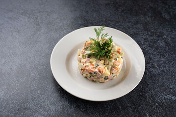 Olivier salad on a white plate and a gray background in a round shape