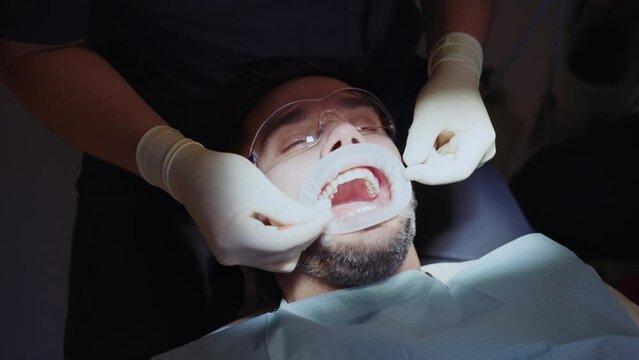 Shot of hands dentist cleans a man's teeth. Hydience and healthy in modern clinic. Healthcare. Protective glasses