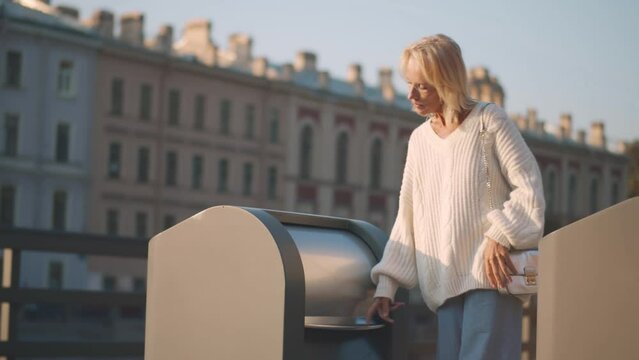 Mature woman throwing empty plastic bottle in bin. Realtime