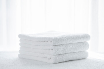 Three white terry towels stacked on a white surface