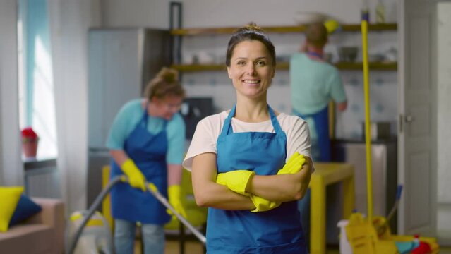 Portrait of female janitor in uniform smiling at camera. Realtime