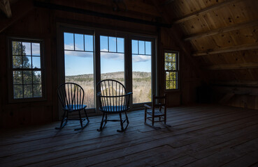 3 empty chairs in a barn facing a view out of large windows in Maine
