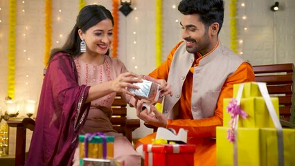 Happy young couple packing gift boxes for festival celebration at home - concept of Indian culture, traditional ethnic wear and relationship bonding