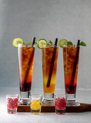 colorful cool ice tea lemonade cocktails in glasses with straw on gray background. Mix glass of cool ice tea lemonade cocktails cool drinks blended fruit passionfruit drinks.