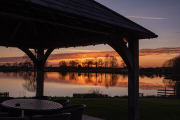 Silhouette of a gazebo next to a lake at sunset in winter