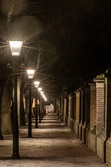The Hague, Netherlands An old cobblestoned street illuminated by street lamps.