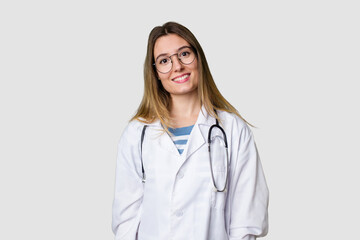 Fototapeta premium Compassionate female physician with a stethoscope around her neck, ready to diagnose and care for her patients in her signature white coat happy, smiling and cheerful.