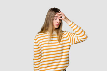 Young blonde posing for a portrait isolated, exuding natural beauty and radiance having a head ache, touching front of the face.