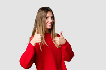 Fototapeta premium Young blonde posing for a portrait isolated, exuding natural beauty and radiance raising both thumbs up, smiling and confident.