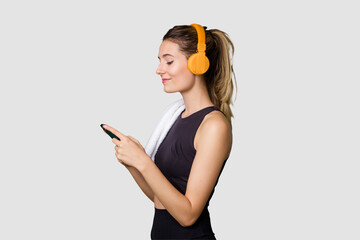 Young sportswoman listening to music, motivated and focused, holding phone