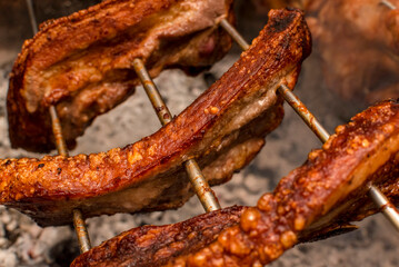 Several pieces of Liempo, or pork belly skewered on a spit and roasted on an oven at a roadside restaurant.