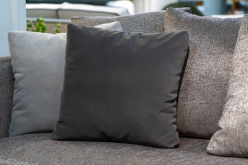 Close up light grey fabric sofa with warm cozy home interior background. Pillows on couch room decoration background