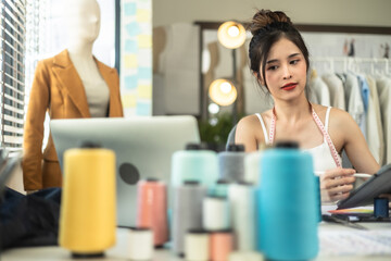 Young Asian woman entrepreneur fashion designer working with laptop computer  at home office.