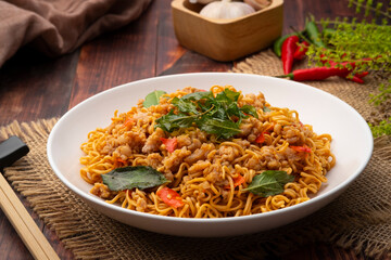 Spicy stir fried instant noodle with minced pork and holy basil leaves in white plate
