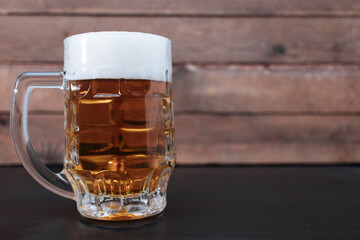 Light beer in a large glass on a wooden background