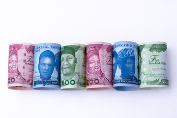 The new Nigerian currency / money, the 200, 500 and 1000 Naira notes, rolled and lying side-by-side on a white background