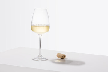 A glass of white wine is on the table. Light background.