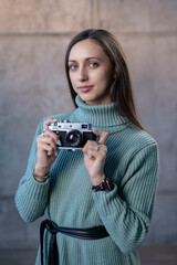 beautiful girl with an old camera in her hands in a green dress. looking at the camera smiling