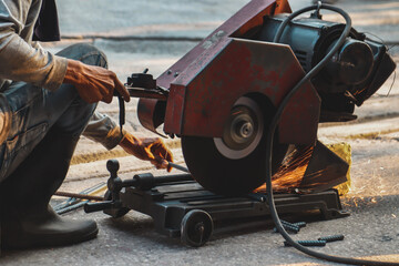 Worker using circular saw to cut steel in industrial factory.