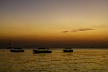 Fototapeta na wymiar Traditional tourist boats at the Indian ocean when sunset. Zanzibar, Tanzania