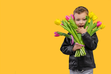Portrait of smiling cute boy with yellow and pink bouquet tulips for Mammy. Spring flowers concept...