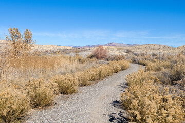 A walking path at Highline Lake State Park in western Colorado leads toward distant desert hills