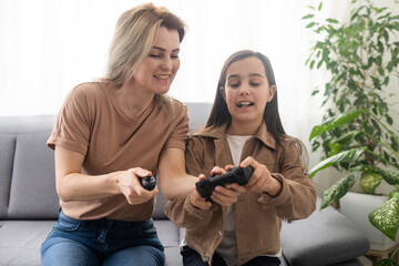 Photo of domestic funny blond lady mom daughter sitting comfy couch hold joystick playing video games stay home safety quarantine spend weekend together best friends living room indoors.