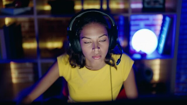 Young african american woman streamer playing video game using computer at gaming room