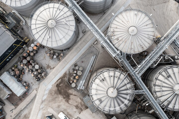 Aerial view above Industrial storage or silo tanks in a row with connecting pipework