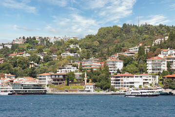 Fototapeta na wymiar Bebek, View from the sea of the green mountains of the Europian side of Bosphorus strait, with docked boats, traditional houses and dense trees in a summer day, Istanbul, Turkey 