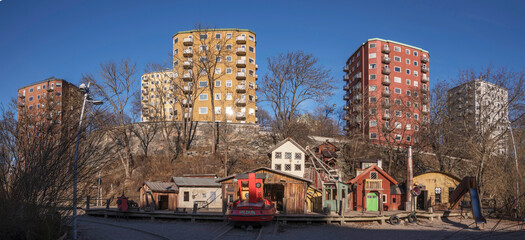 Panorama, high apartment houses in different colors at the hill Danviksklippan and a playground a...