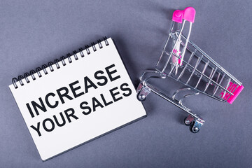 Increase your sales. Business concept. Inscription on notebook with mini shopping cart