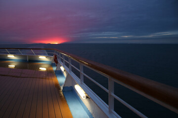 Beautiful final moments of the sunset with pink clouds over a cruise ship deck; a relaxing way to...