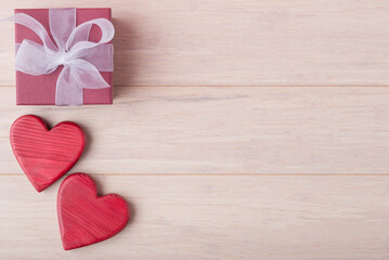 Decorative Valentines hearts and red gift box on light wooden background with copy space....