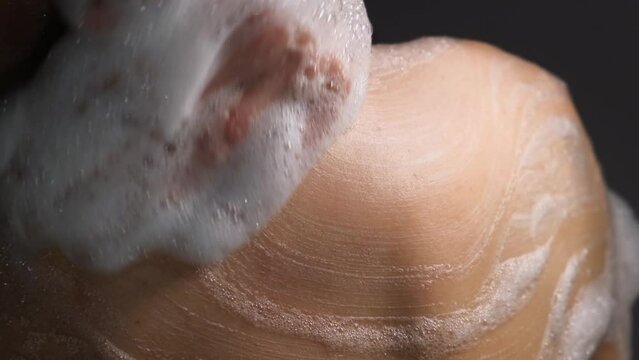 A man bathes in the bathroom rubbing the gel over his body, close-up