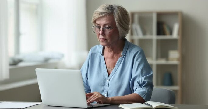 Tired mature woman work on laptop, feels tired, take off glasses to reduce eyestrain and fatigue after long usage of device. Eyesight problem, computer vision syndrome or digital eye strain symptom