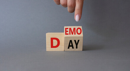 Demo Day symbol. Businessman hand points at turned wooden cubes with concept words Demo Day....