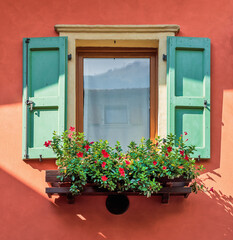 Wooden window decorated with flowers. Typical facade of the old Provencal retro house with windows. Flowers under shuttered.