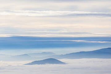 Naklejka na ściany i meble Beautiful foggy winter scenery with clouds and mountain peaks