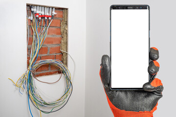 Builders hand with phone. Smartphone with blank screen near place for electrical equipment. Concept...