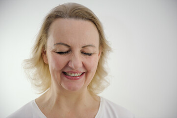 face of middle-aged woman with blond hair on a white background close-up she lowered her eyes...