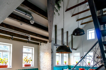 Interior design in a cafe. View of the ceiling in the restaurant. Designer ceilings, decorative wooden beams, metal chandeliers and lamps. Ventilation pipe along the ceiling.