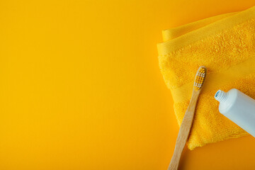 bamboo toothbrush on yellow background with yellow towel and toothpaste